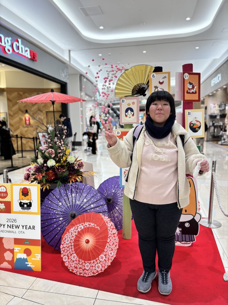 ショッピングセンター内の新年っぽいフォトスポットでピースする利用者さん