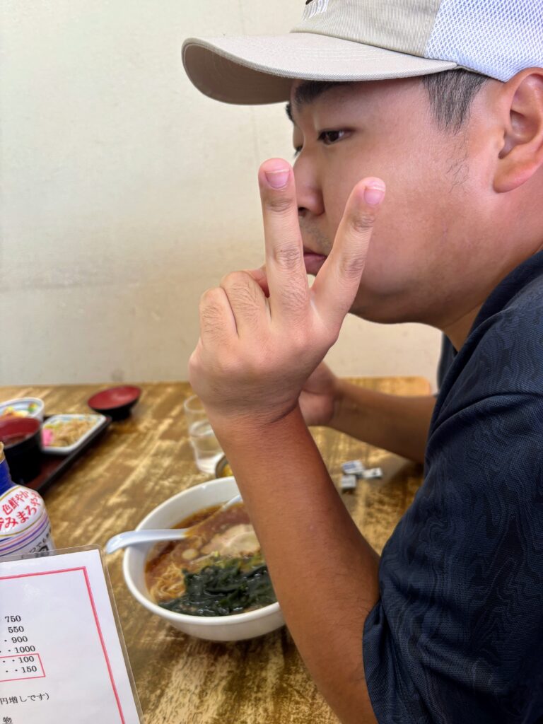 ラーメンを食べながらピースサインをする２０代男性利用者さんの横顔
