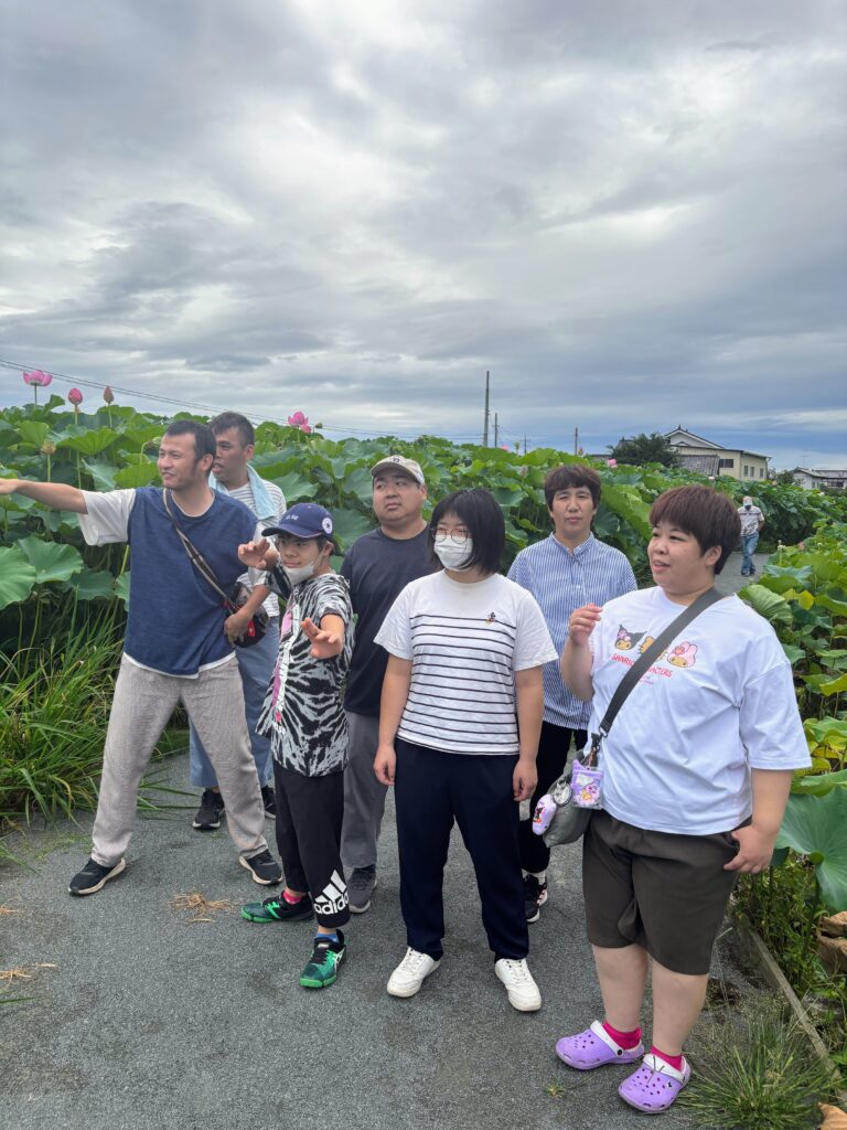 ハスの畑の中、横並びの利用者さんたち（男性四名、女性三名）